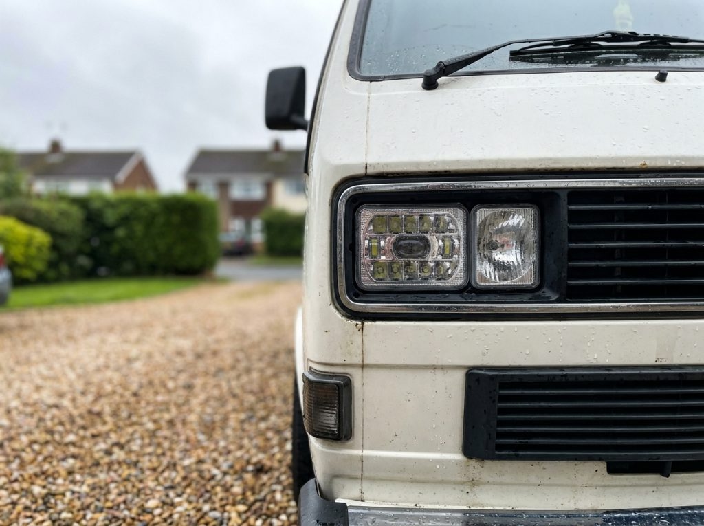 Phares LED aftermarket montés sur un Volkswagen Transporter T3 garé sur une allée en gravier