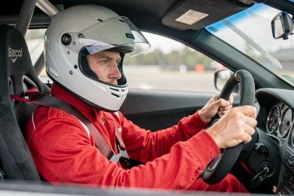 Pilote en combinaison de course concentré dans l'habitacle d'une voiture de stage de pilotage sur circuit