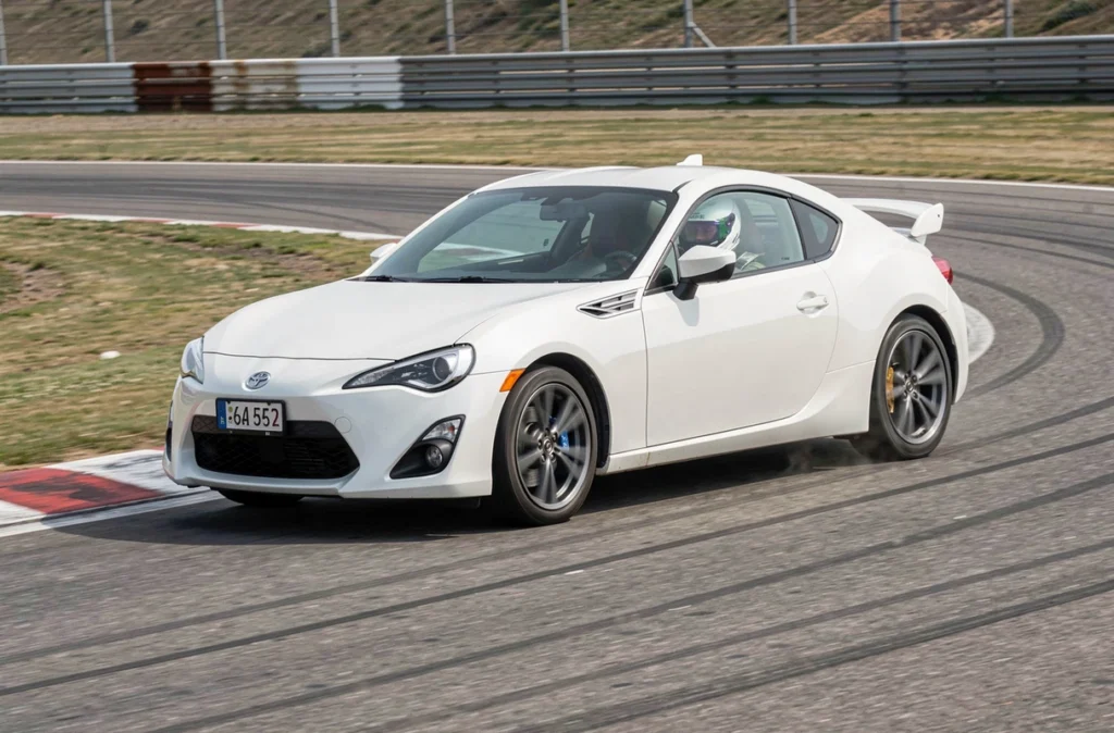 Toyota 86 street legal en pleine action dans un virage sur circuit avec pilote casqué et configuration route